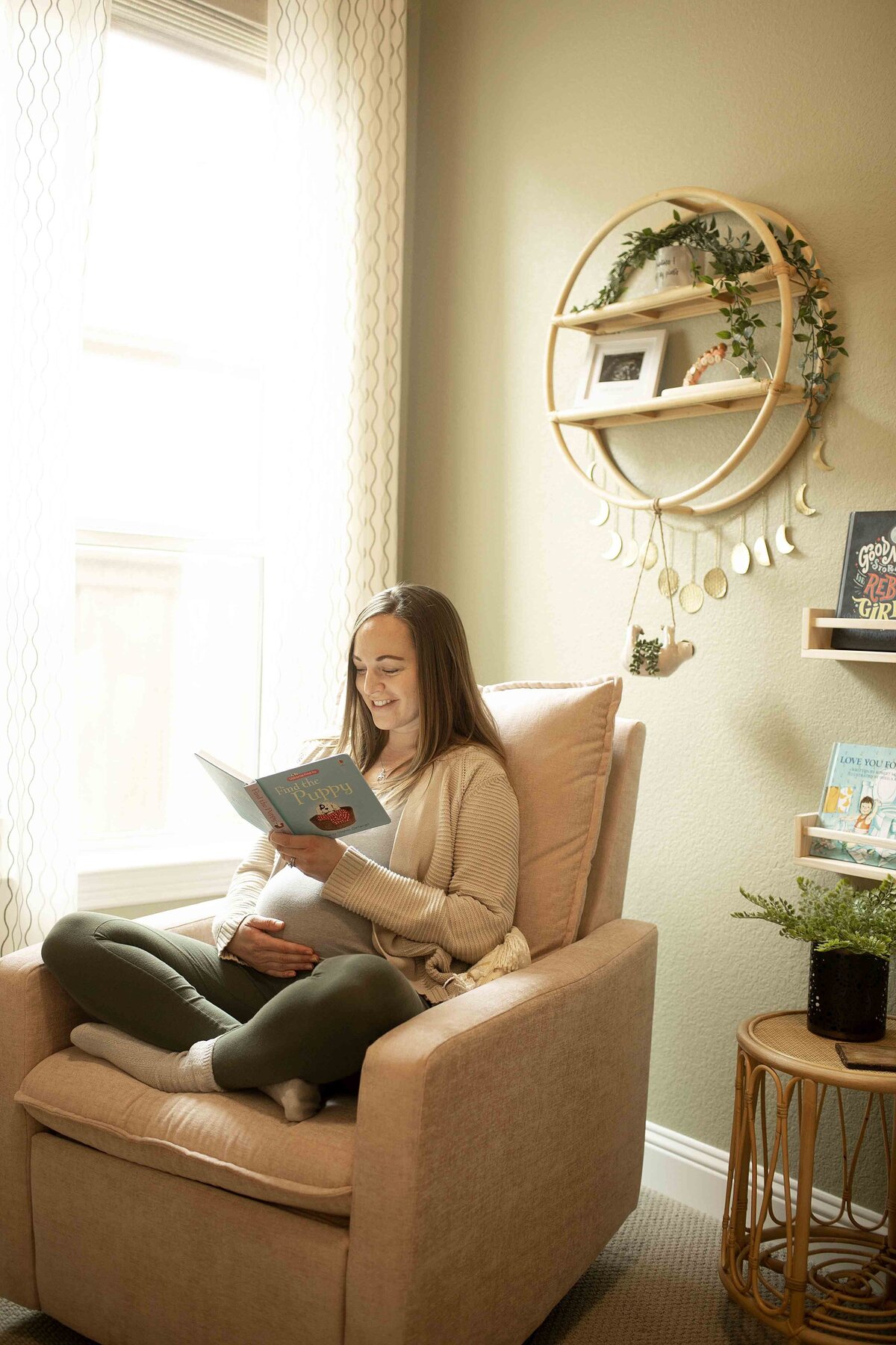A cozy maternity photo of mom sitting in the nursery, reading a book while gently cradling her baby bump, surrounded by soft nursery decor and natural light, captured by Chunky Monkey Photography.