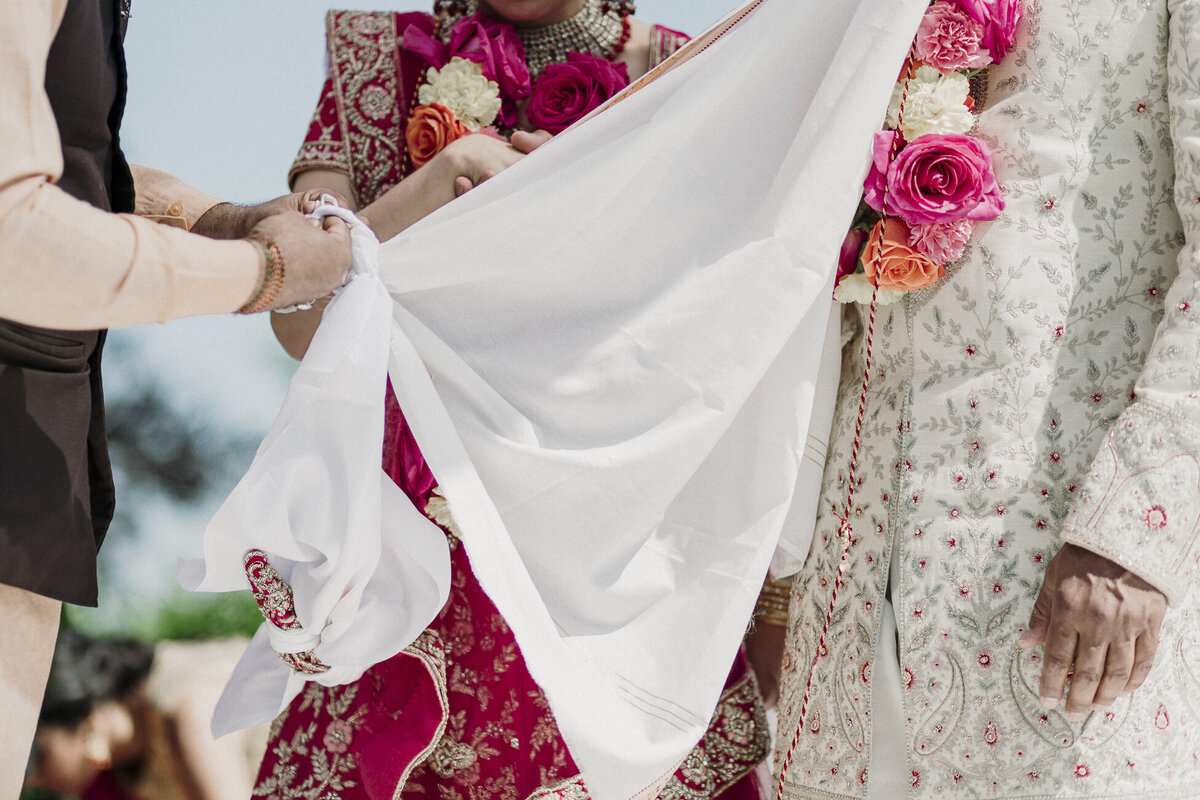 Close-up of a Hindu wedding ceremony ritual at a private estate, with the couple's garments tied together. Captured by Mira Park Photography.