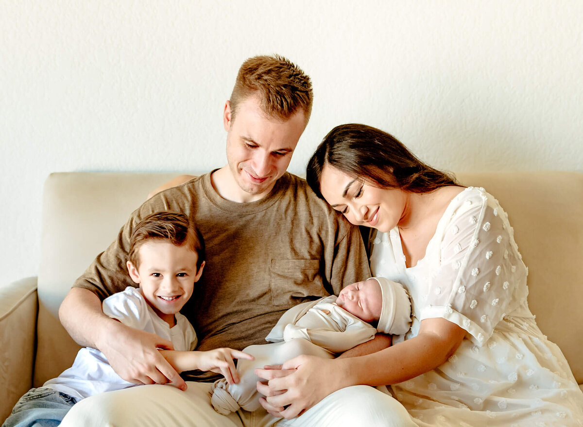 Family cuddling newborn on the couch at in-home newborn session in Phoenix