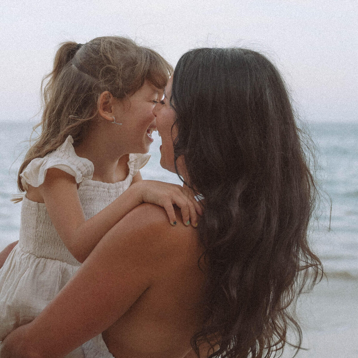 Mother and daughter laughing together during a candid Laguna Beach family photography session in Orange County, California.