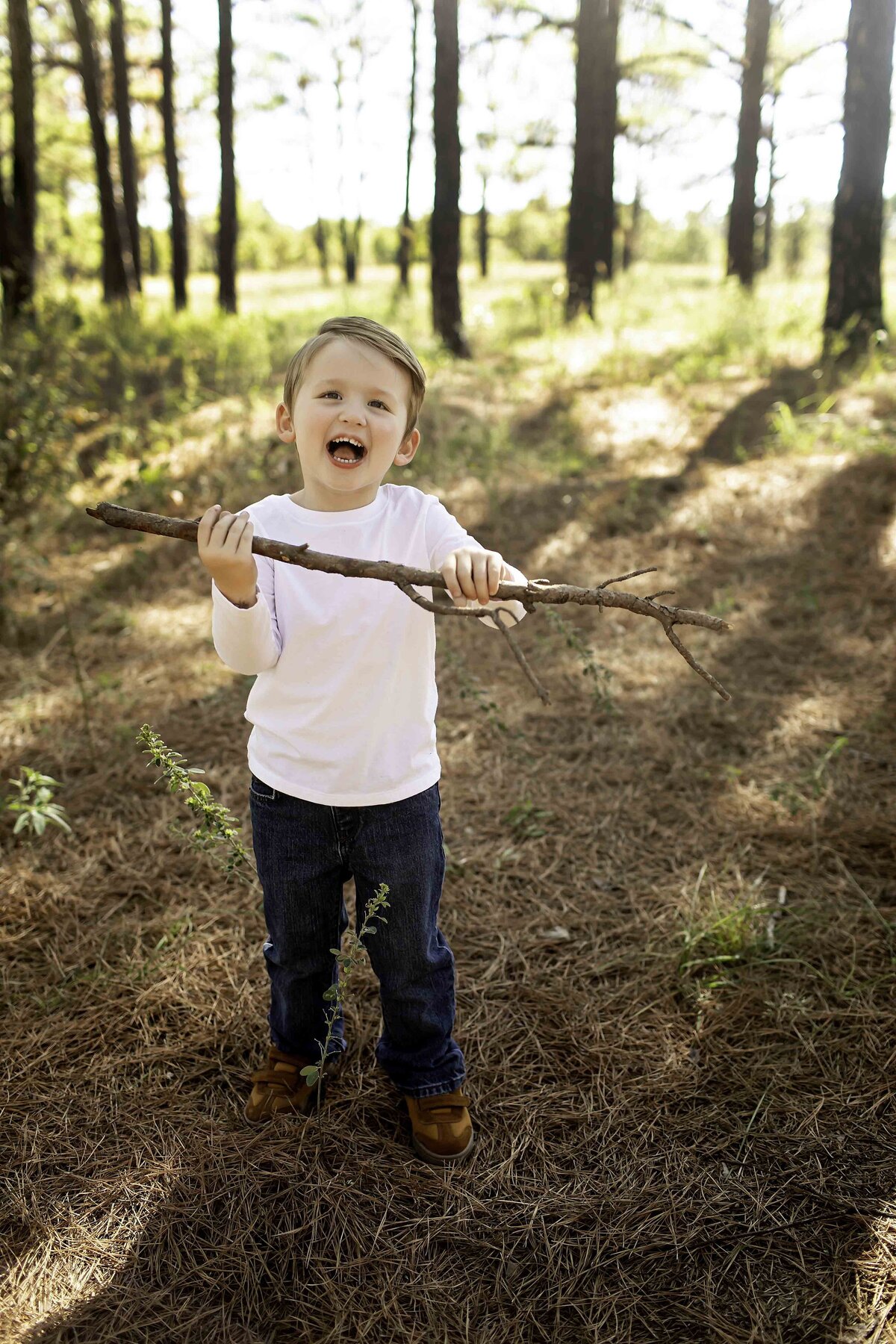 Big brother looking up at the tall pine trees, surrounded by nature, with a joyful expression on his face