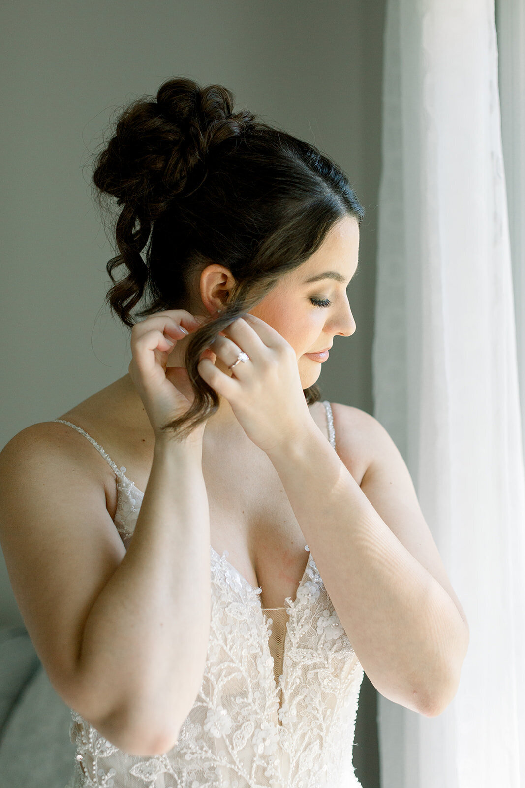 Bride adjusting earring with elegant bridal updo and soft glam makeup in Chicago, IL.