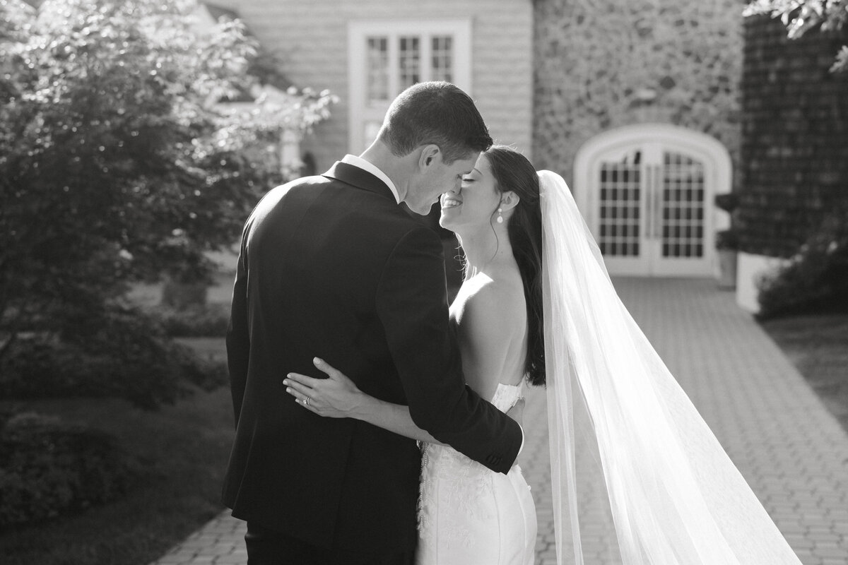 Bride and groom wrap their arms around each other in front of The Ryland Inn, NJ.