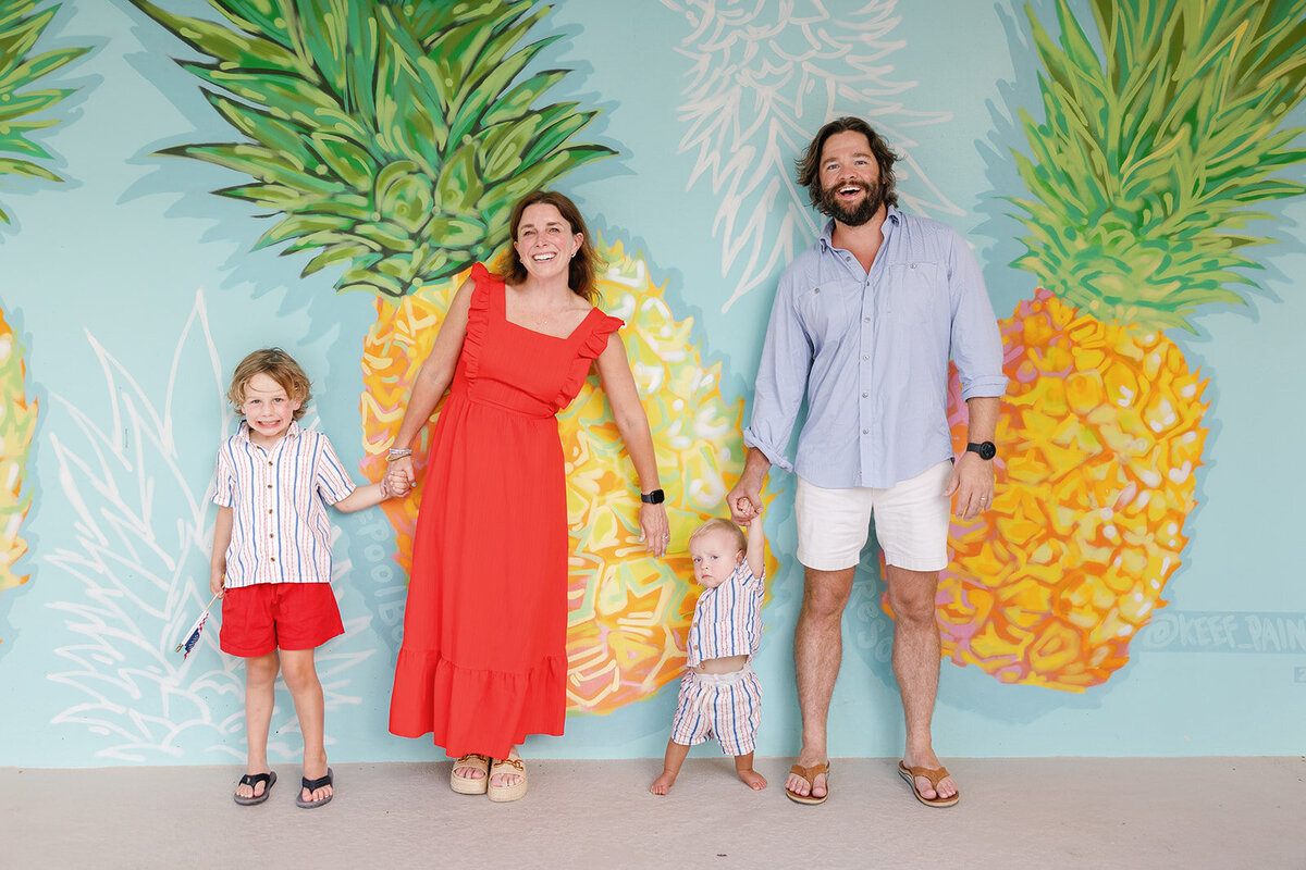  A family poses in front of a bright pineapple mural during a vibrant Florida Keys portrait session.