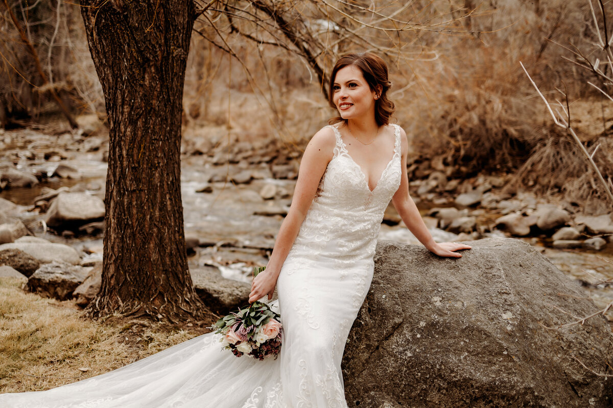 Bride sitting on a large rock at a Denver wedding venue