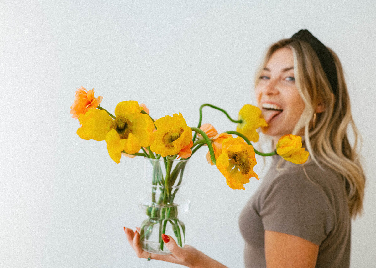 Florist holding a custom floral arrangement of whimsical yellow flowers