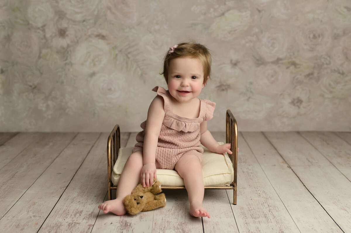 smiling toddler sitting on small metal bed