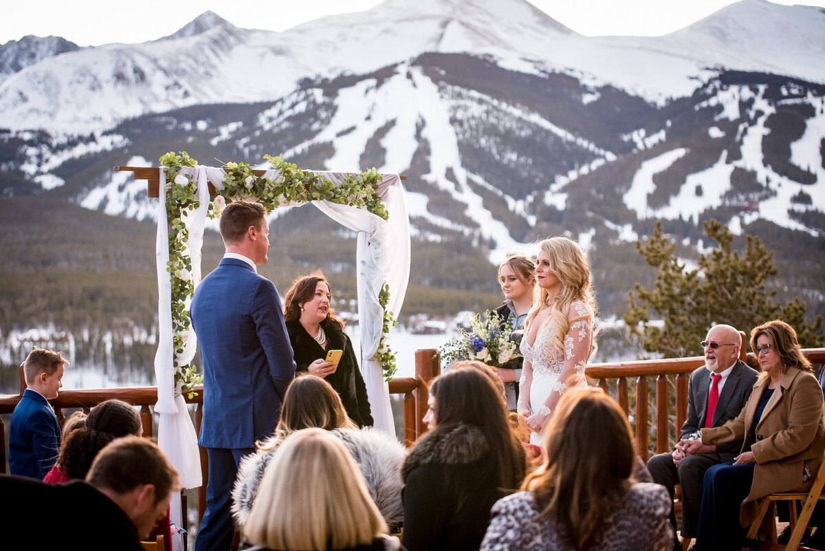 A wide angle shot of a wedding ceremony with a snowy Colorado mountain landscape in the background.