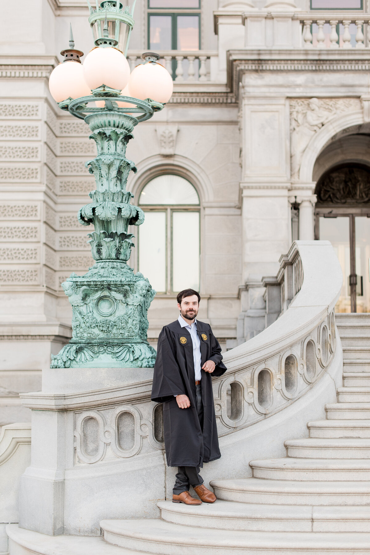 male grad standing on  marble staircase