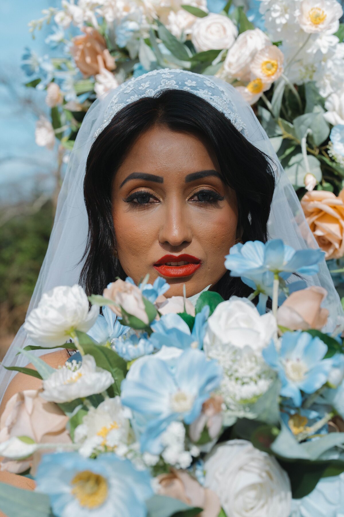 Bride holding bouquet, looking at the camera.