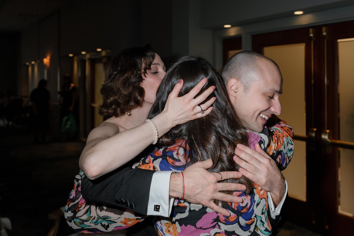 bride-and-groom-hugging-friend-after-speech-at-wedding
