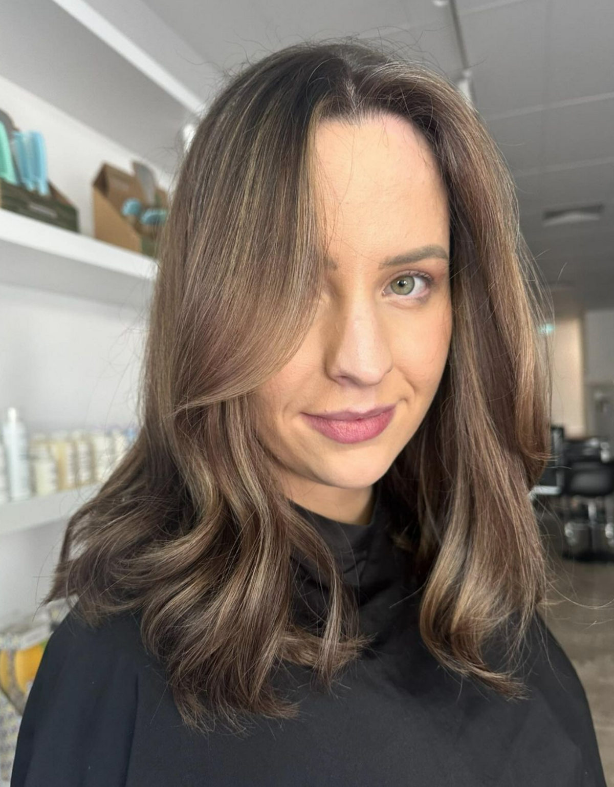 Woman I black hairdresser cape with freshly coloured hair - brunette with blonde pieces