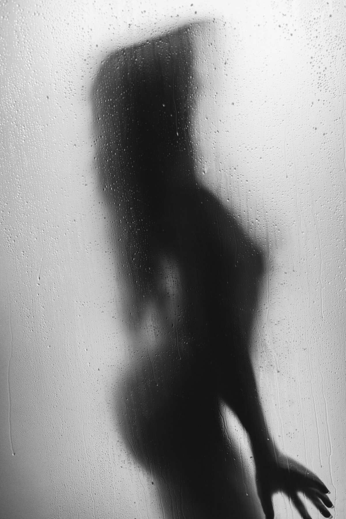 Female silhouette behind a shower door with her hand stretched out