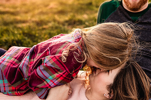 Toddler kissing mom who is laying on her back in field at Wagon Hill in Durham NH by Lisa Smith Photography