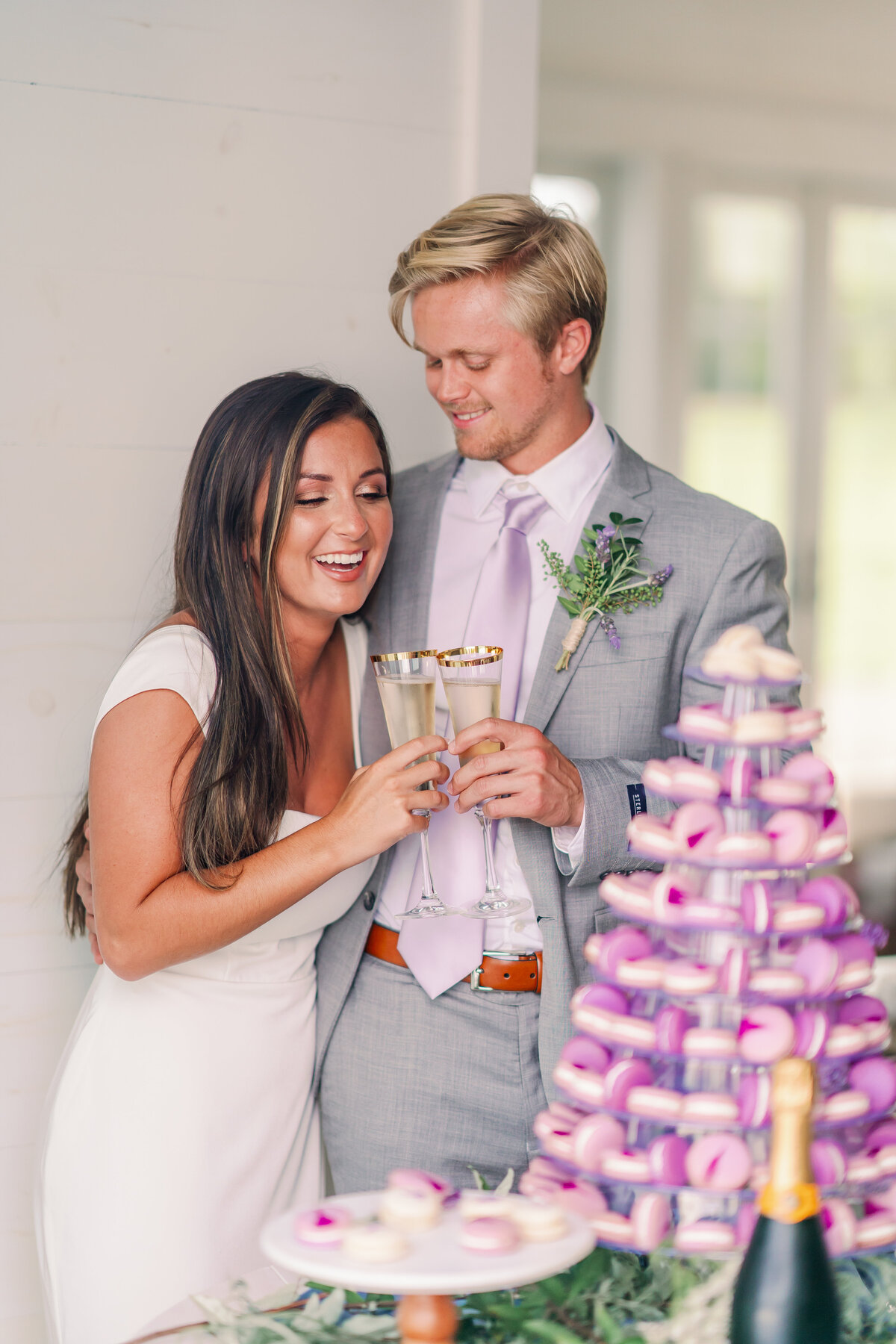 Couple cheers with champagne near macaroon wedding cake