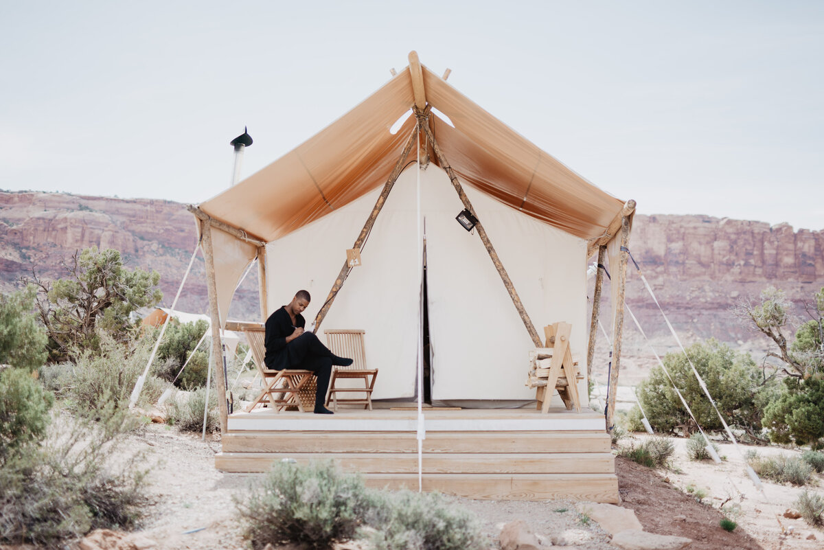 Utah Elopement Photographer captures man sitting on bench outside teepee