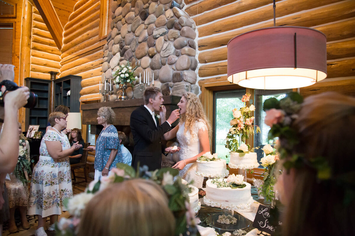 a bride and groom feeding each other cake at their mountain wedding