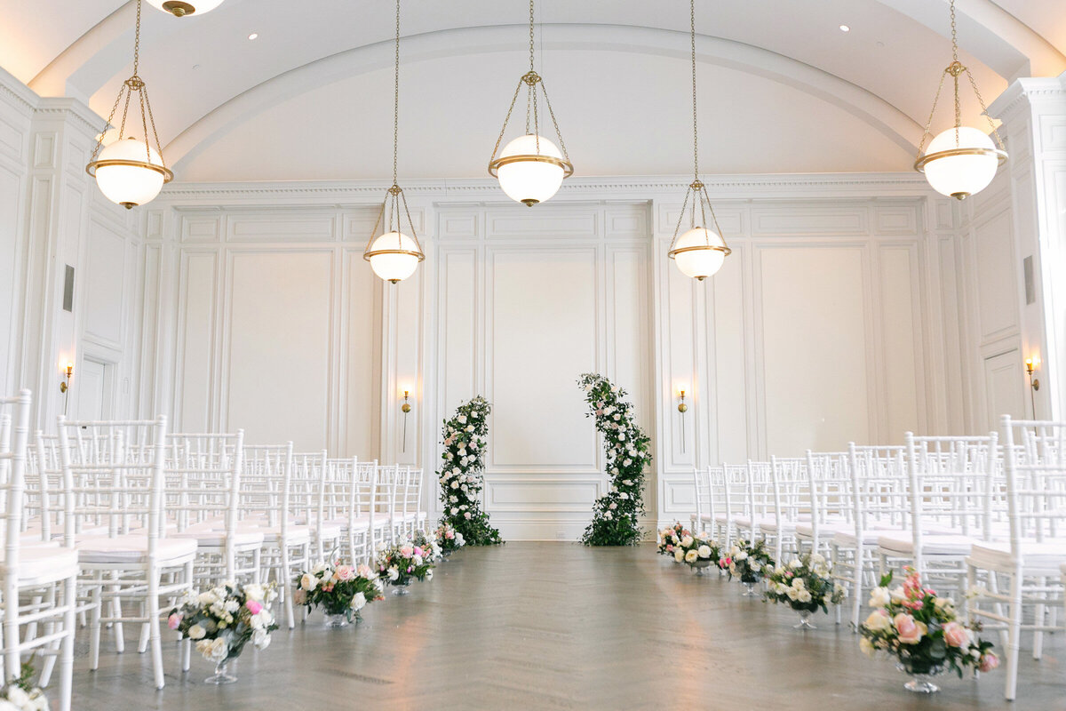 empty Governor’s Room at The Adolphus in Dallas set up for a wedding ceremony, featuring a floral arch and floral arrangements along the aisle, highlighting the elegant venue décor.