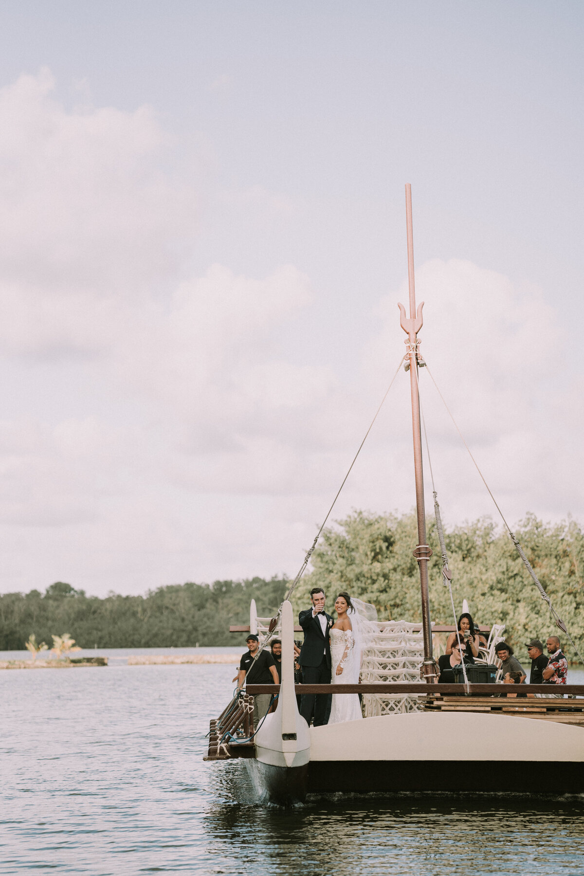 Bride and groom riding on the boat transportation through the Kualoa Ranch pond