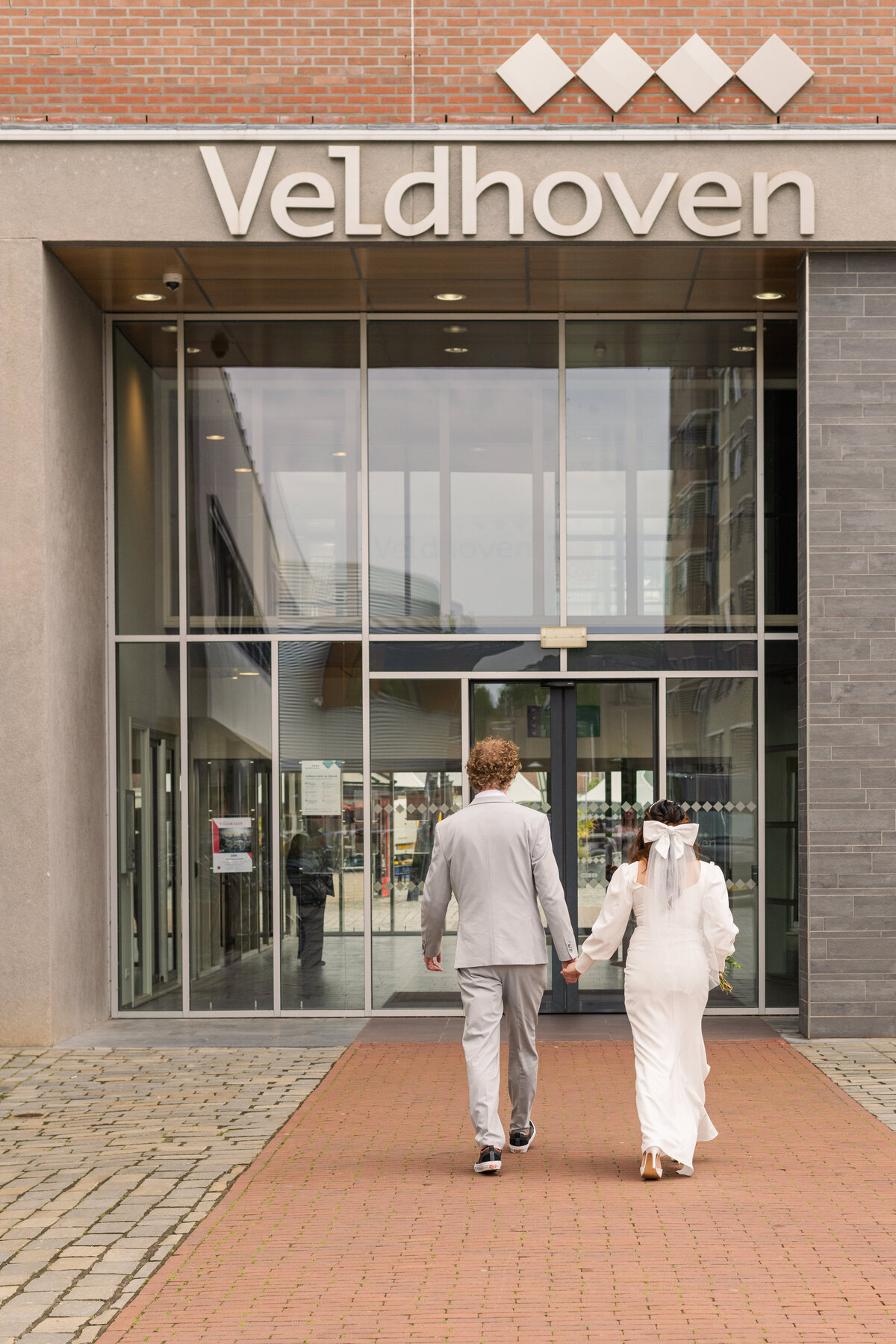 A bride and groom walk into the local municipality building in Veldhoven for their micro wedding