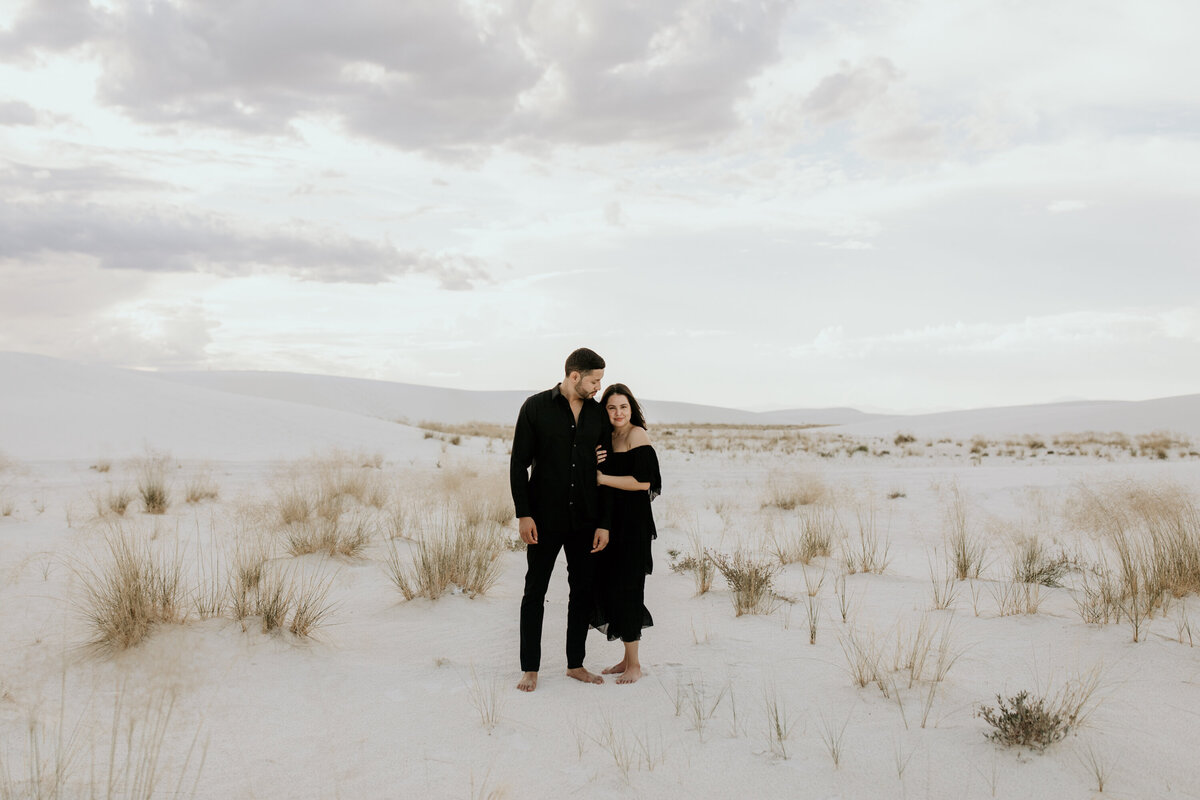 engaged couple standing together in the desert white sand dunes