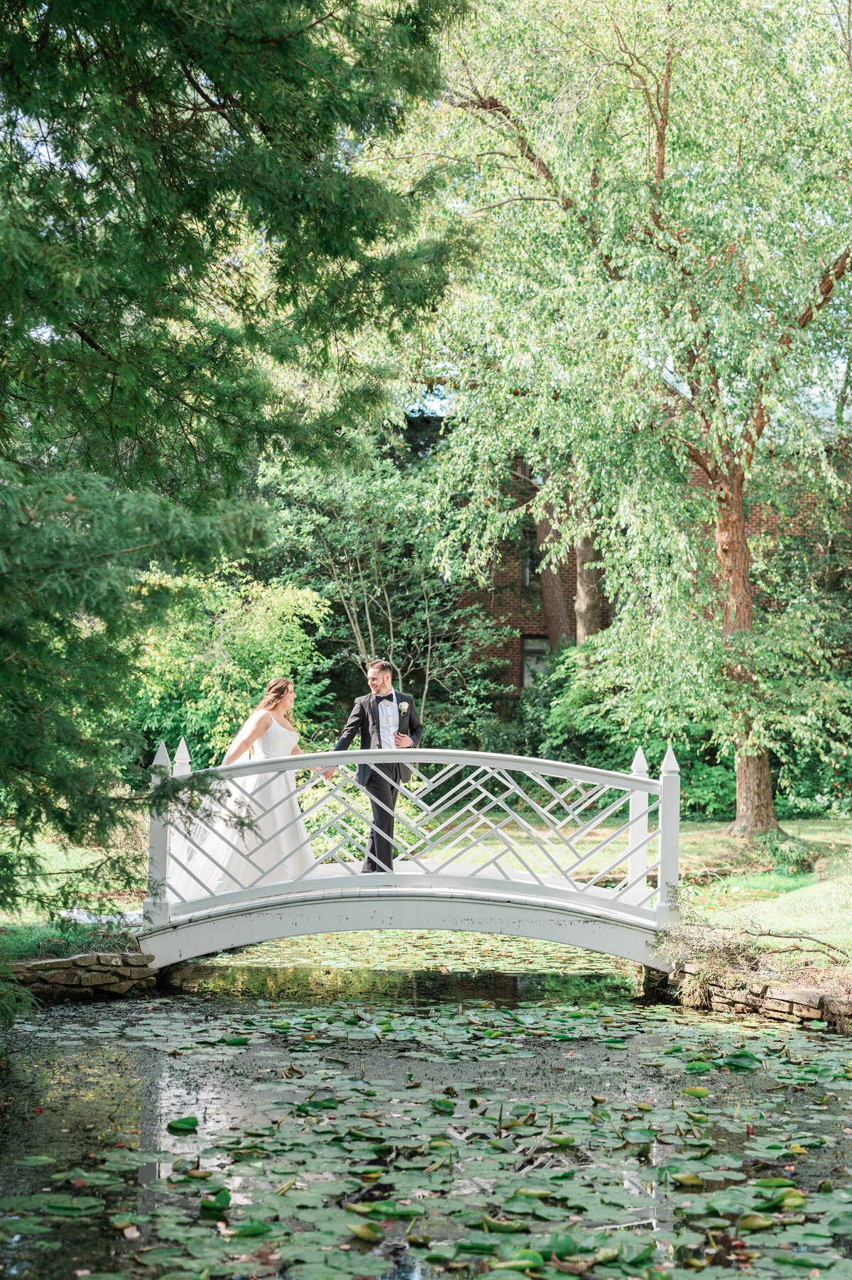 A wedding couple walking over a small bridge