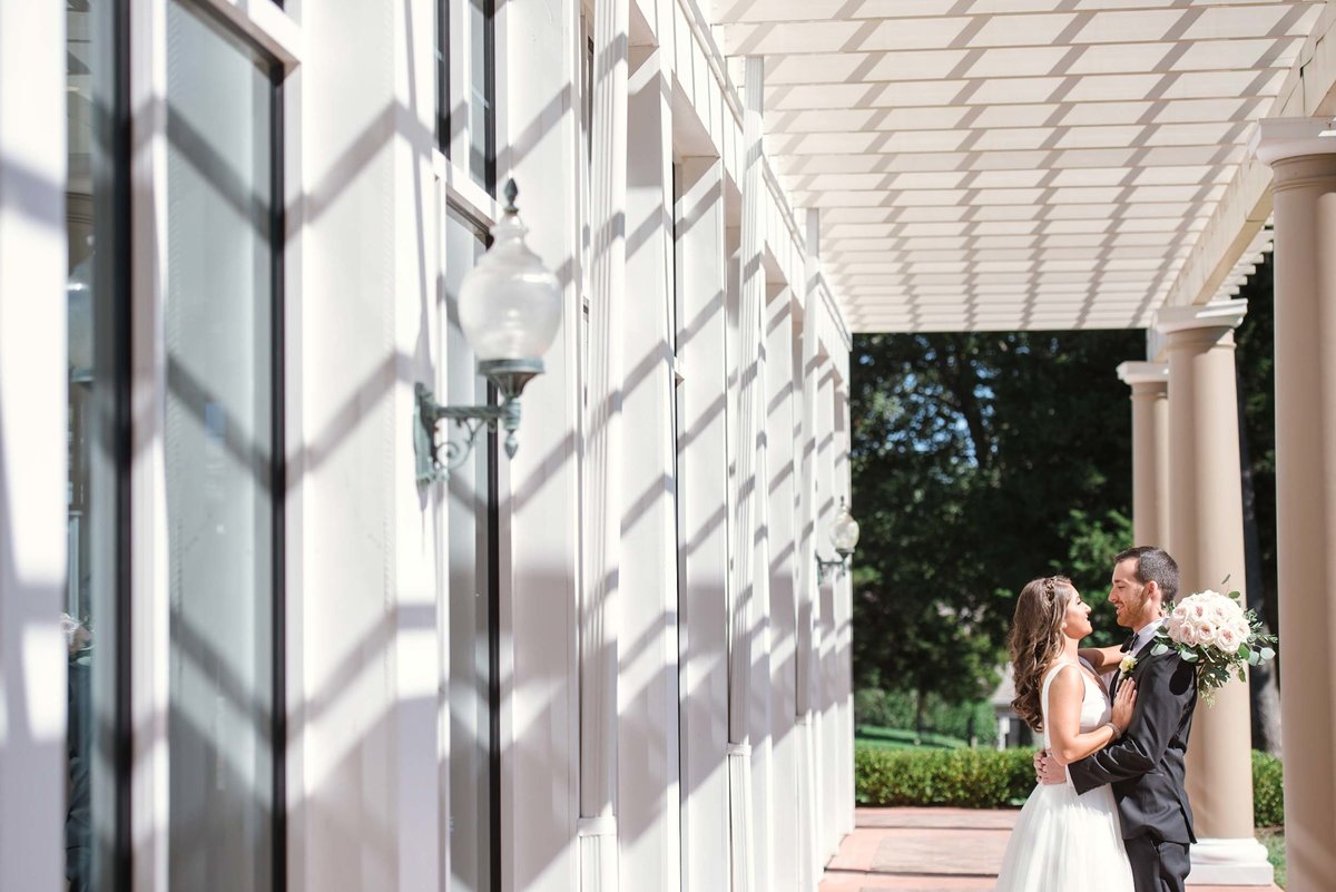 Bride and groom looking at each other in each other's arms on the side of the outdoor reception area at Stonebridge Country Club