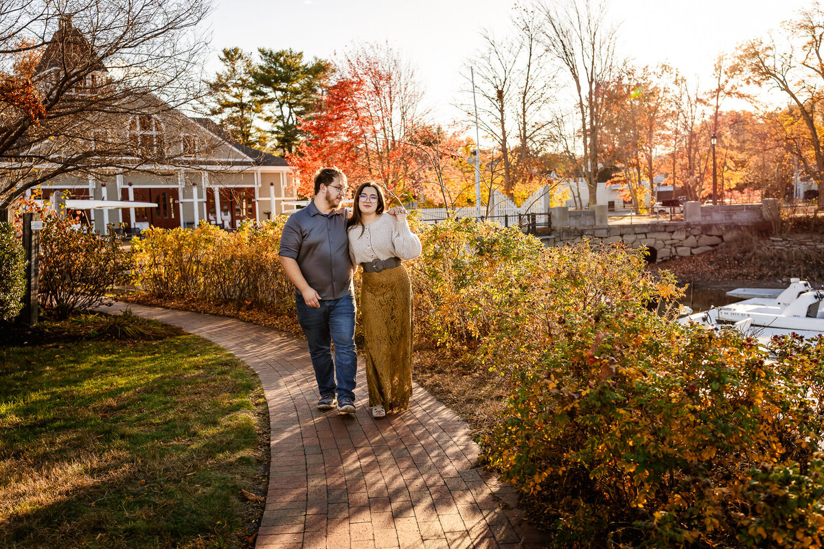 Couple walking down brick path at fall engagement photography session
