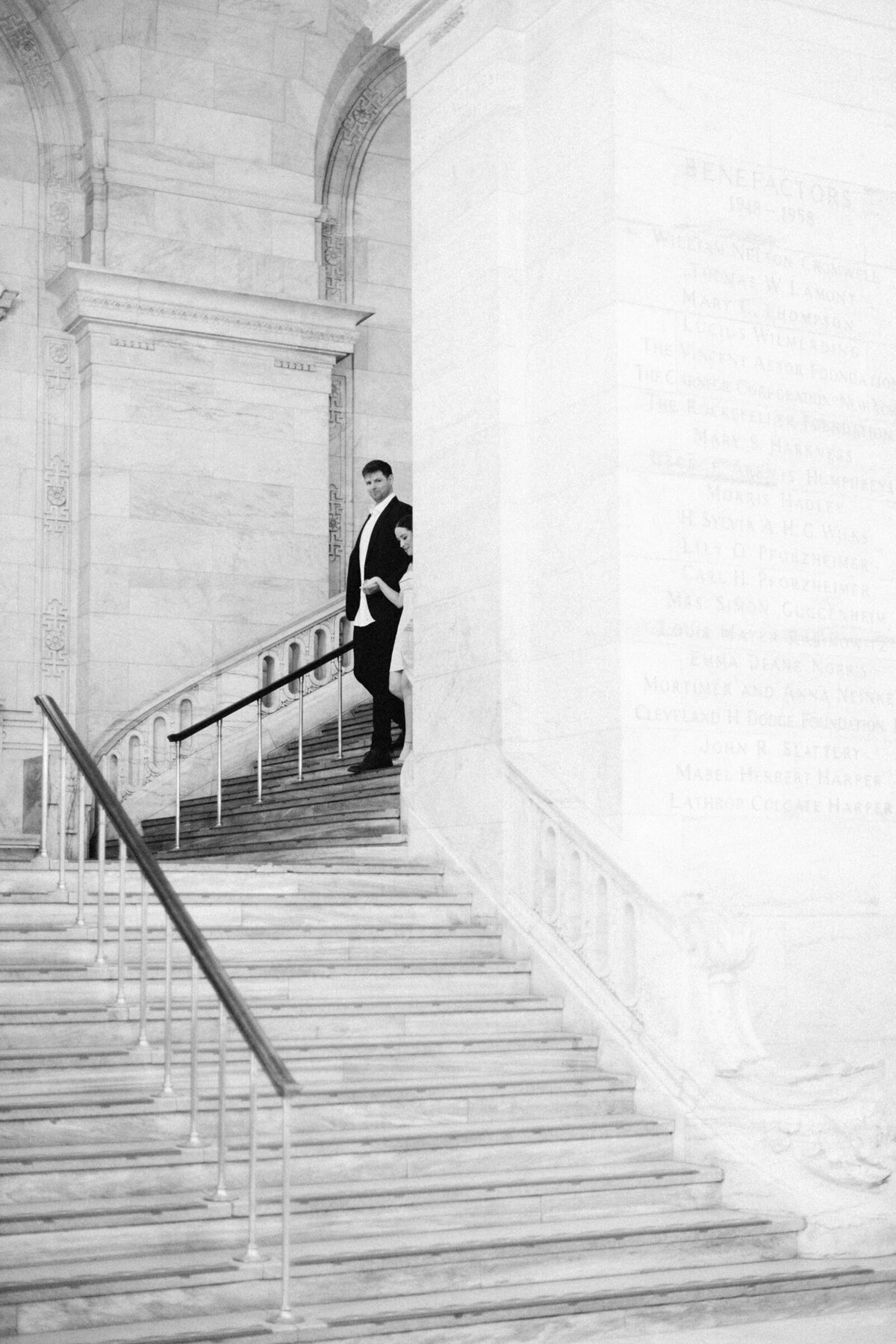 couple walking down marble stairs in the new york public library engagement session