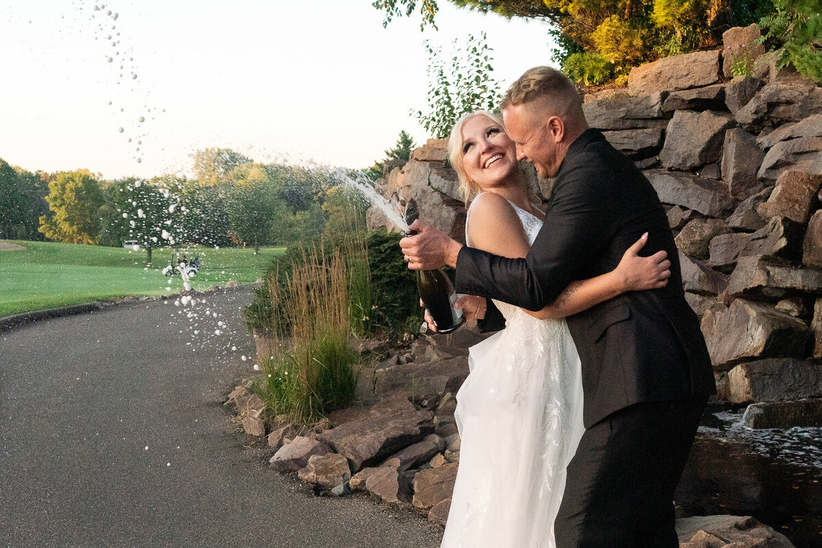 Bride and groom snuggle with wedding party in front of Mill City Museum in Minneapolis, Minnesota.