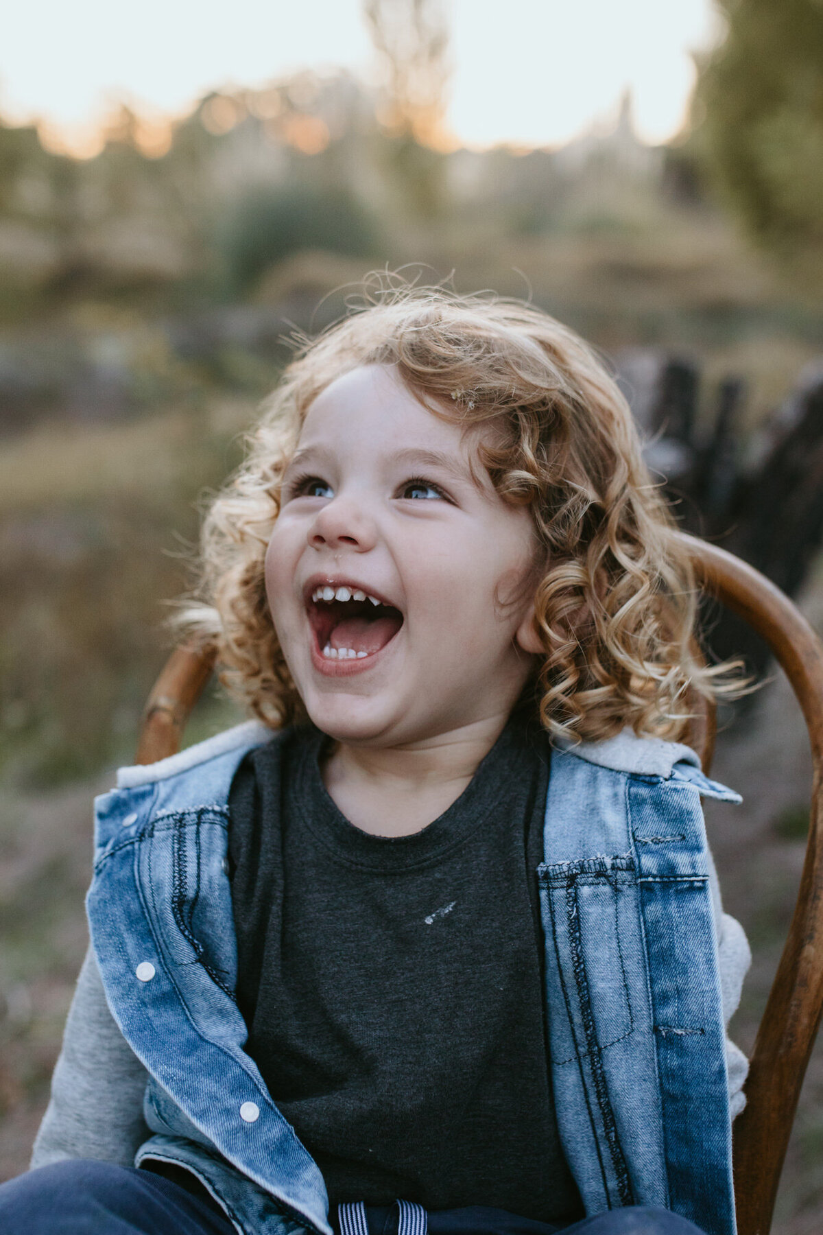 Cute curly haired brown eyed boy laughing with his mouth wide open. 