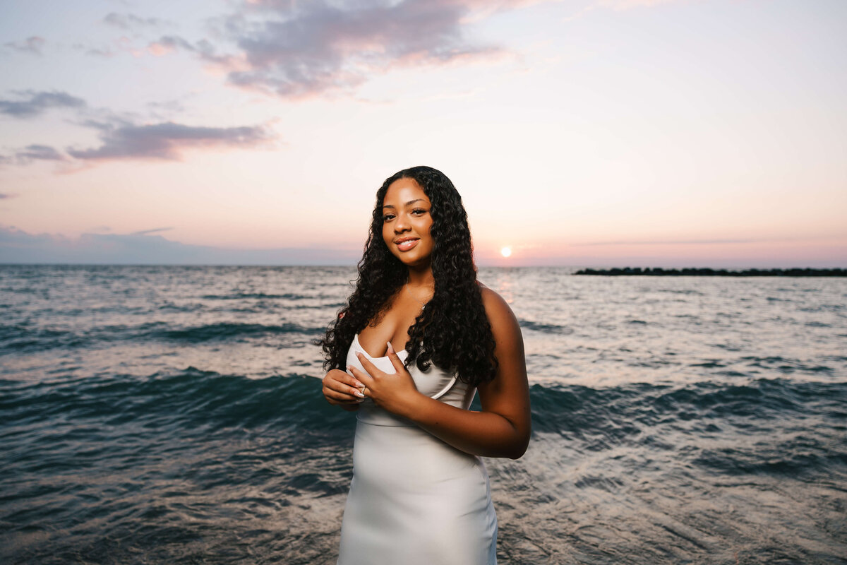 Senior portrait of a girl standing with the sunset in the background in Erie Pa