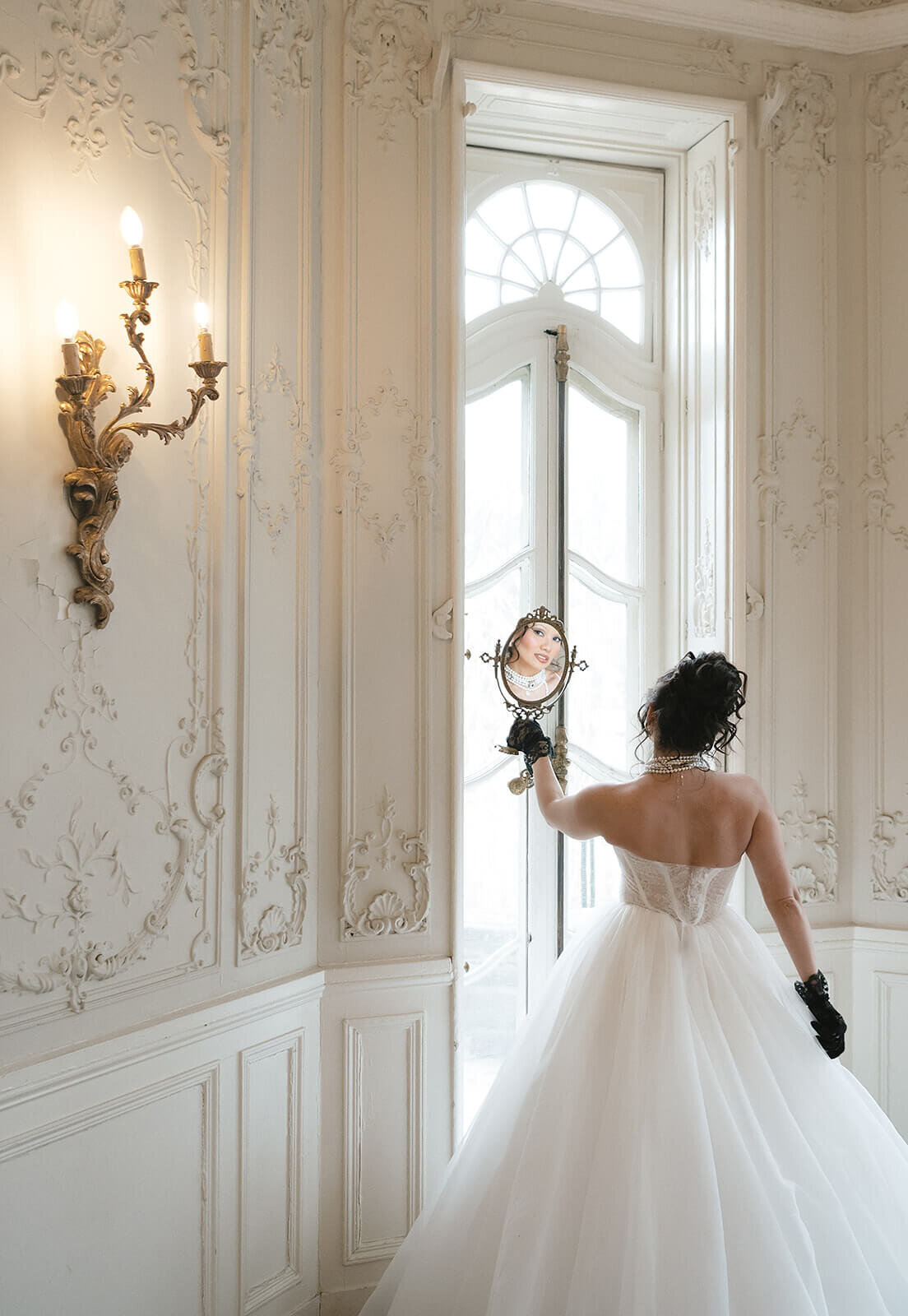 Bride in a fairytale ballgown wedding dress gazing into an antique mirror; timeless bridal hair and makeup by Klover Beauty in Maryland.