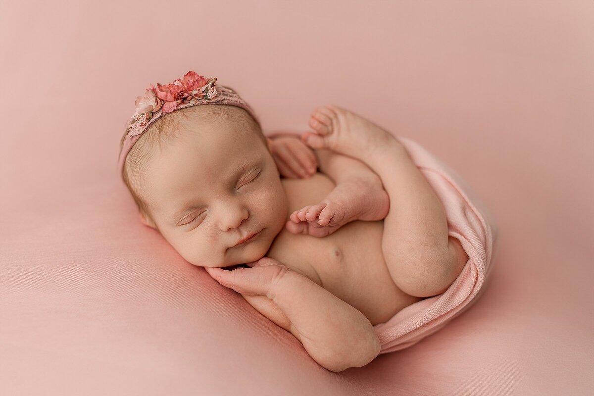 Baby girl in pink posed newborn photography studio