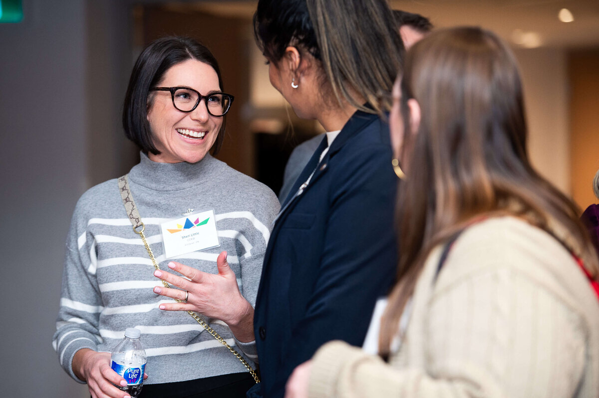 a woman smiling at another guest during a corporate reception at the Westin Hotel.  Captured by Ottawa Event Photographer JEMMAN Photography COMMERCIAL