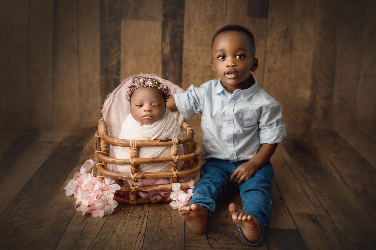 big brother poses next to baby sister at hamilton, ON newborn photography studio