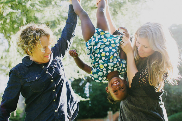 Portrait of two women holding a child upside down as a candid shot