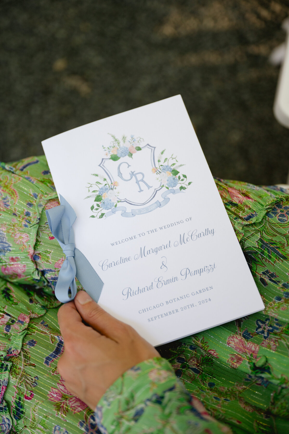 Wedding invitation held by a guest at the Chicago Botanic Gardens.