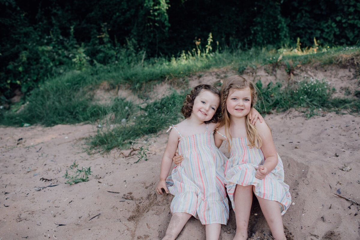 sisters-hugging-and-sitting-together-on-beach