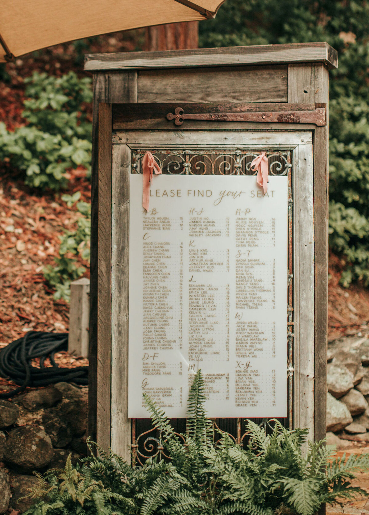 White acrylic calligraphy seating chart hung on a rustic door