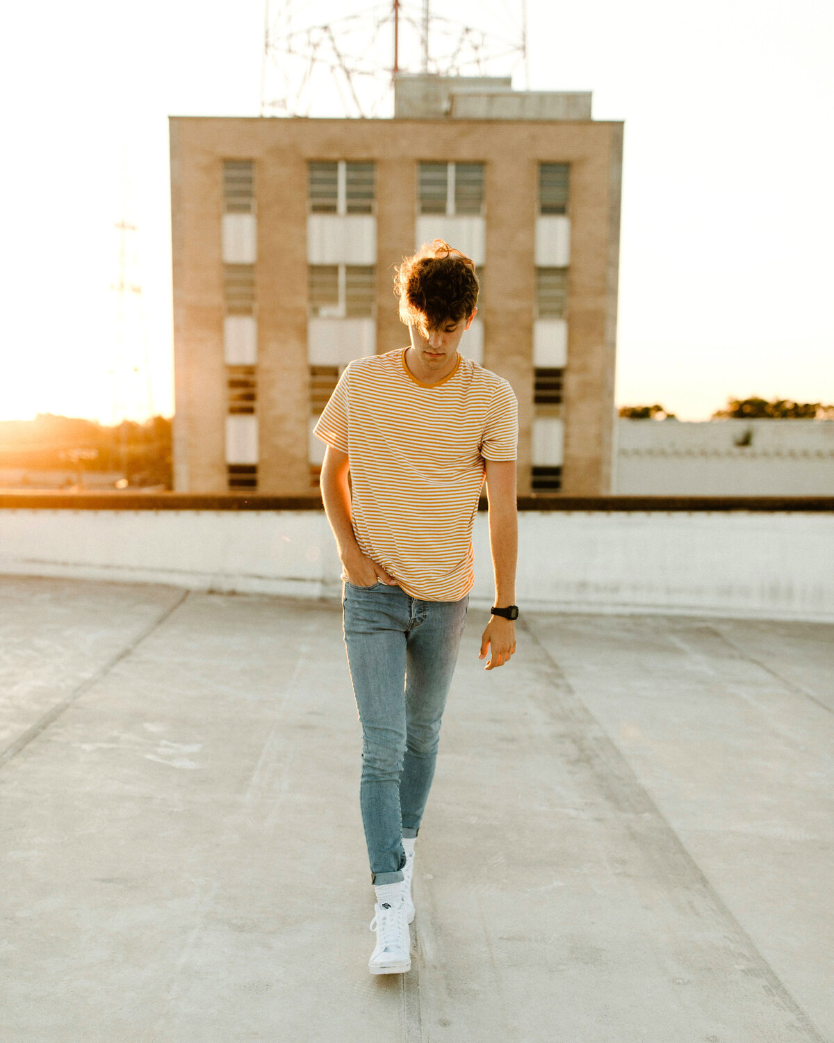 High school senior boy walking on rooftop.