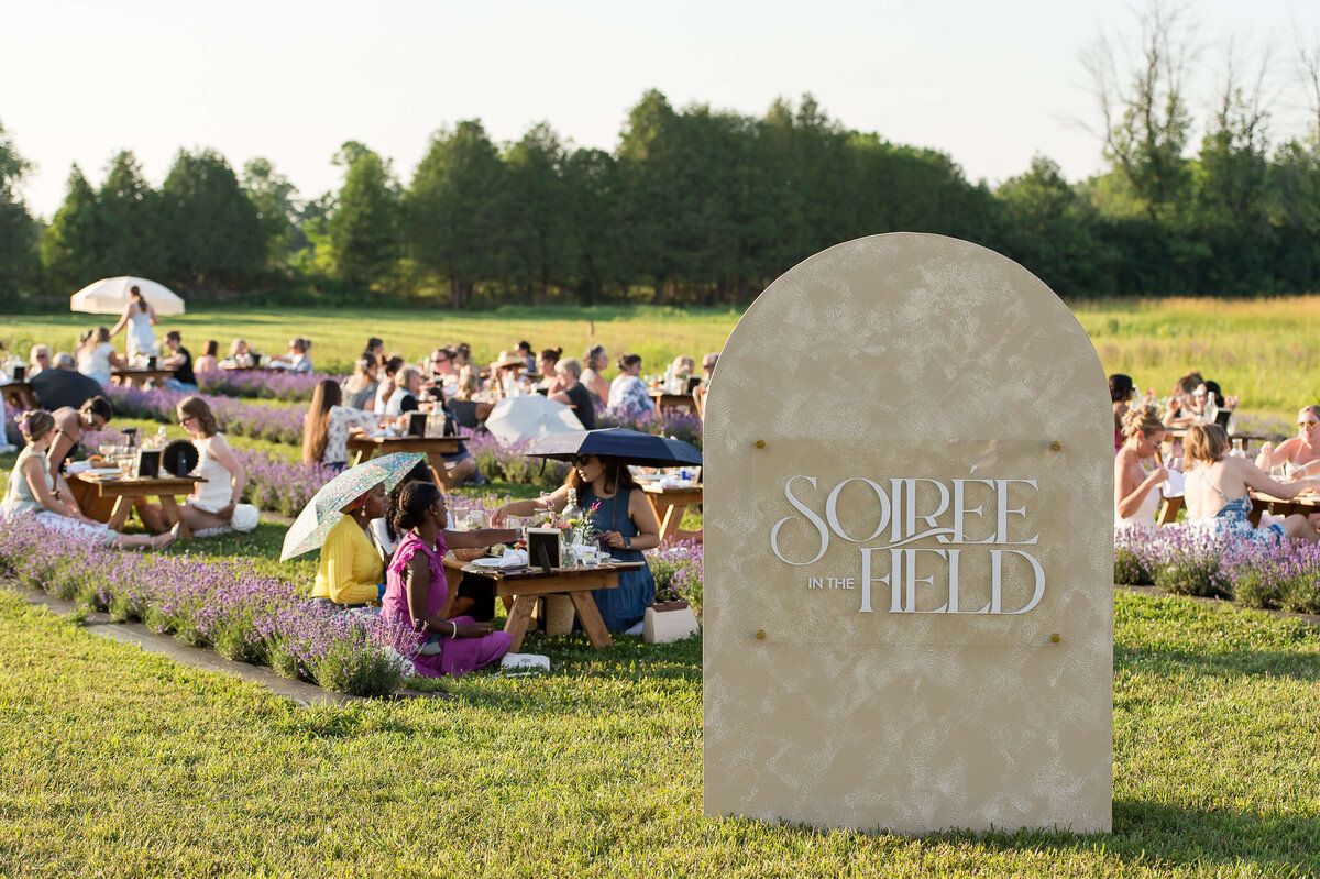 Signage of Soiree in the Field and guests in the background.  Captured by Ottawa Event Photographer JEMMAN Photography COMMERCIAL