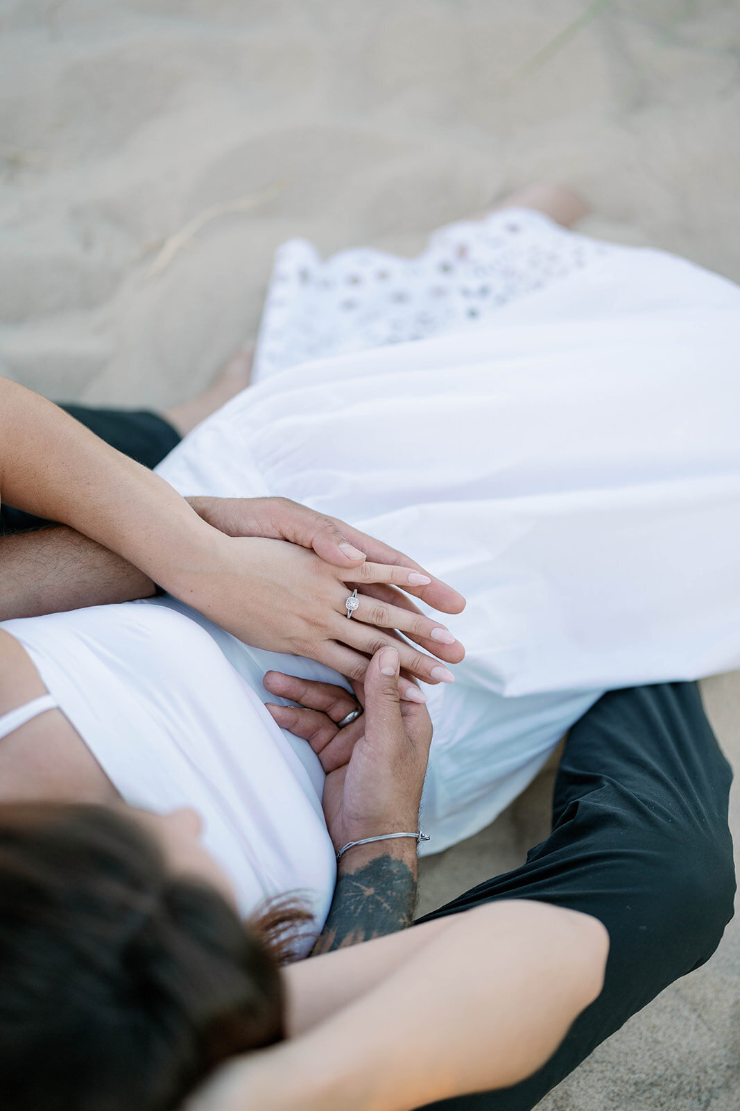 Couple relaxing in the sand during sunset engagement photos on Lake Michigan in New Buffalo