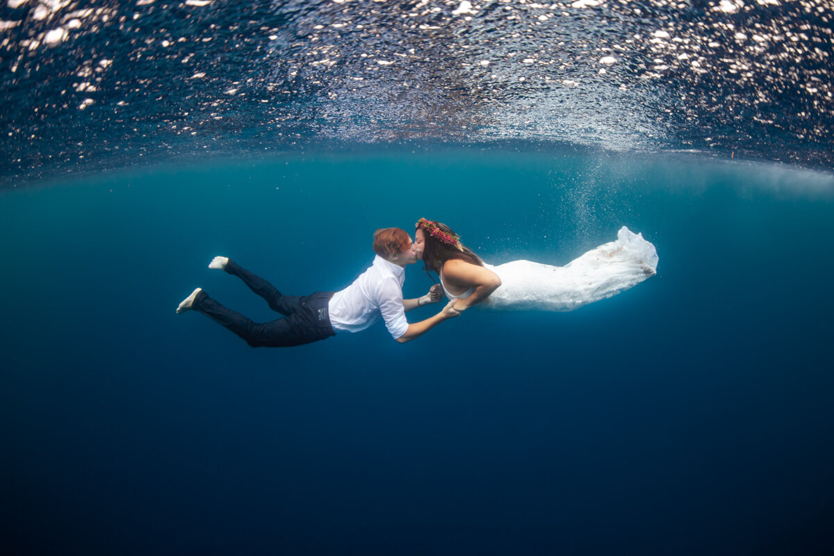 bride and groom kissing underwater with flower crown