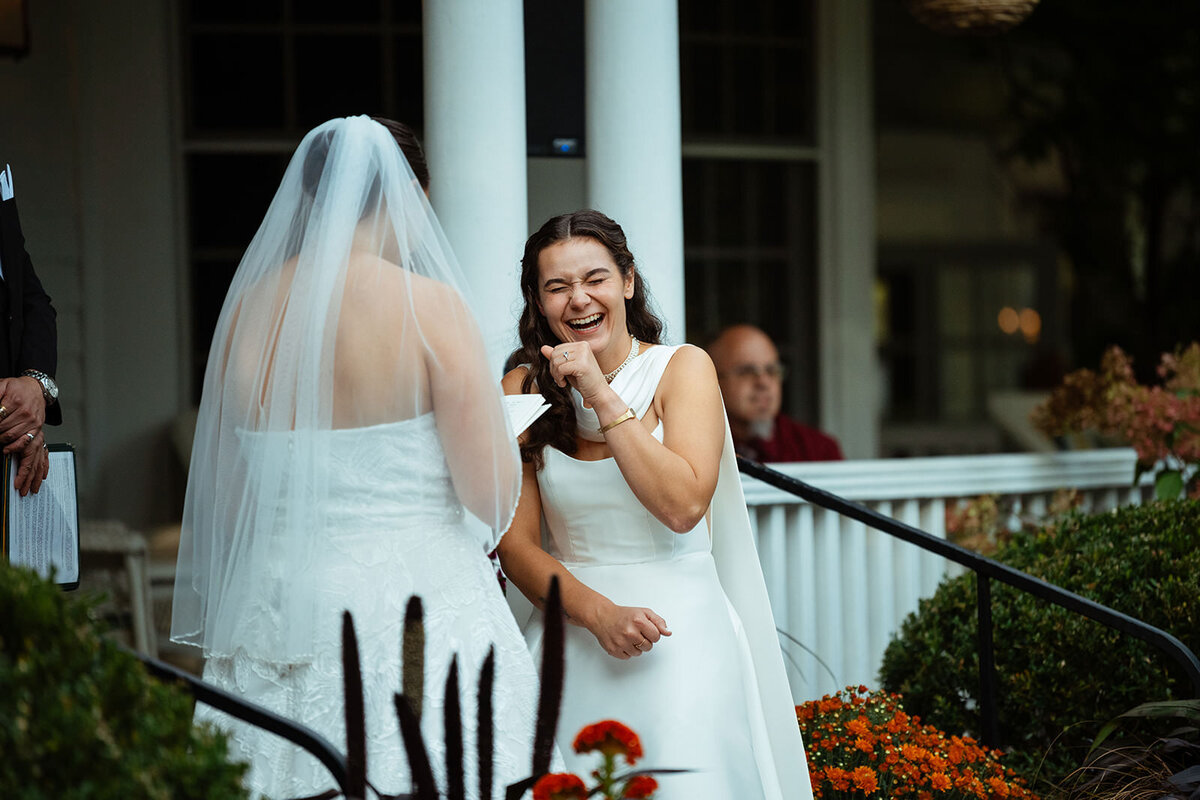 Bride laughing while other bride shares wedding vows