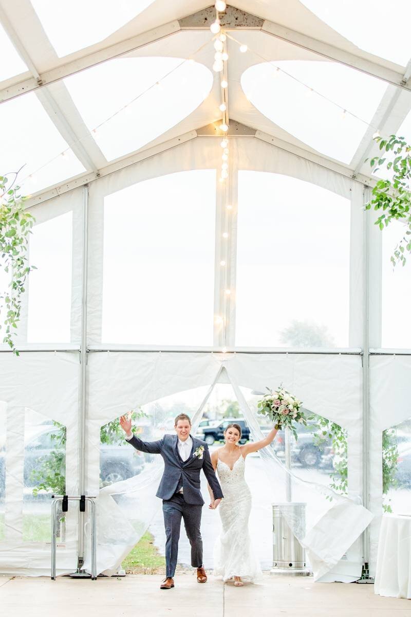 bride and groom have grand entrance in clear top tent