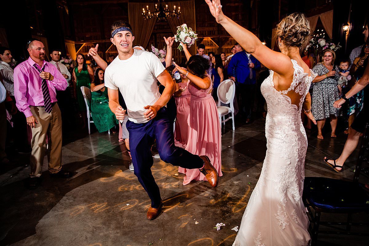 Groom dancing around on the dance floor with his bride as guests watch and dance