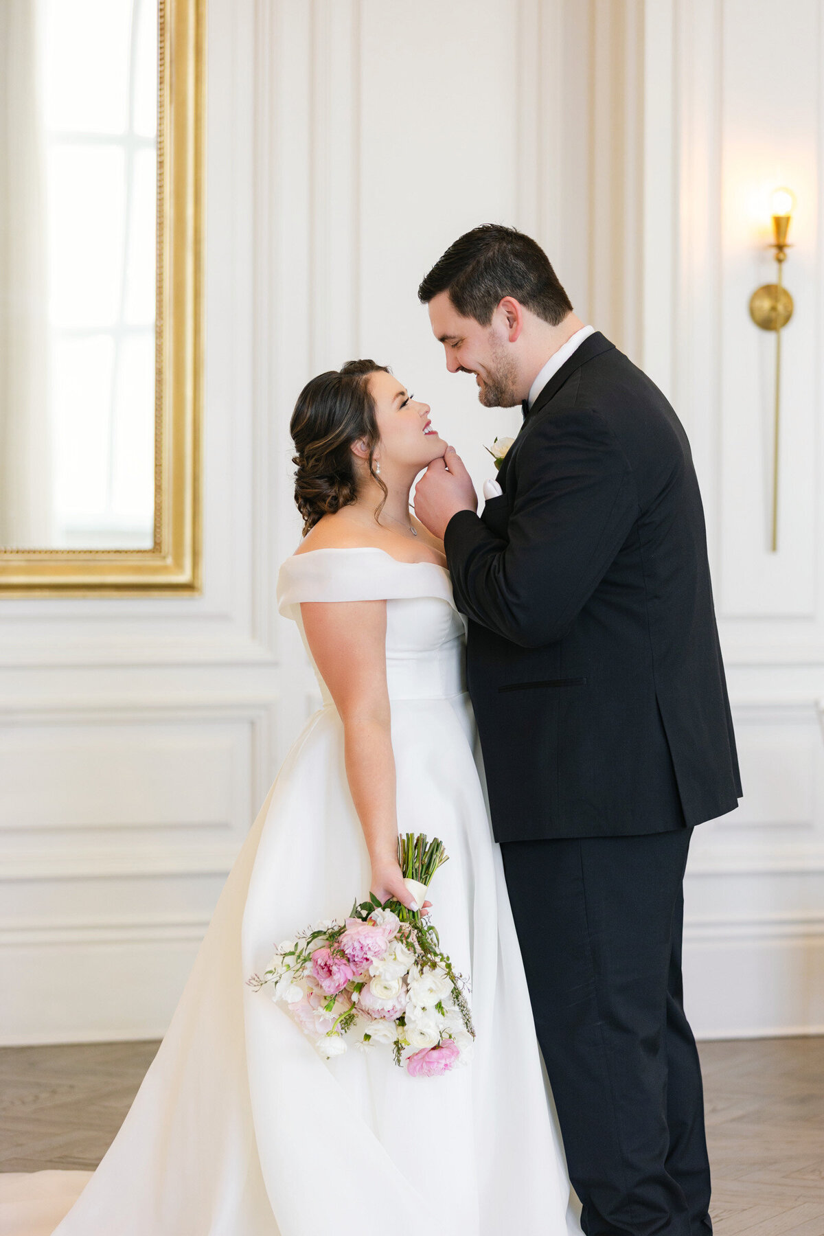 portrait of the couple in the Governor’s Room at The Adolphus in Dallas, with the groom holding the bride’s chin as he leans in for a kiss, capturing a romantic and intimate wedding moment.