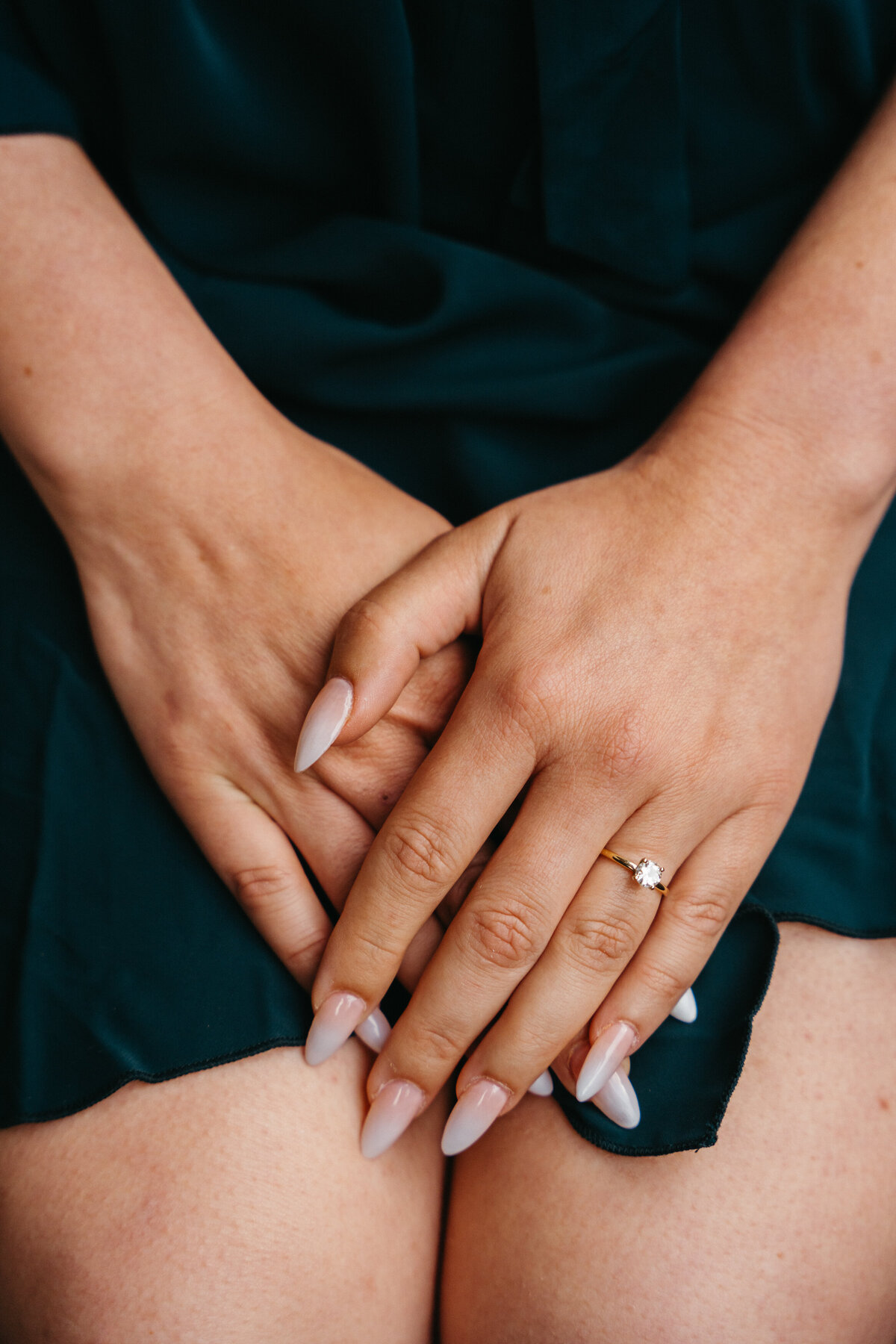 Close-up of bride’s clasped hands with engagement ring