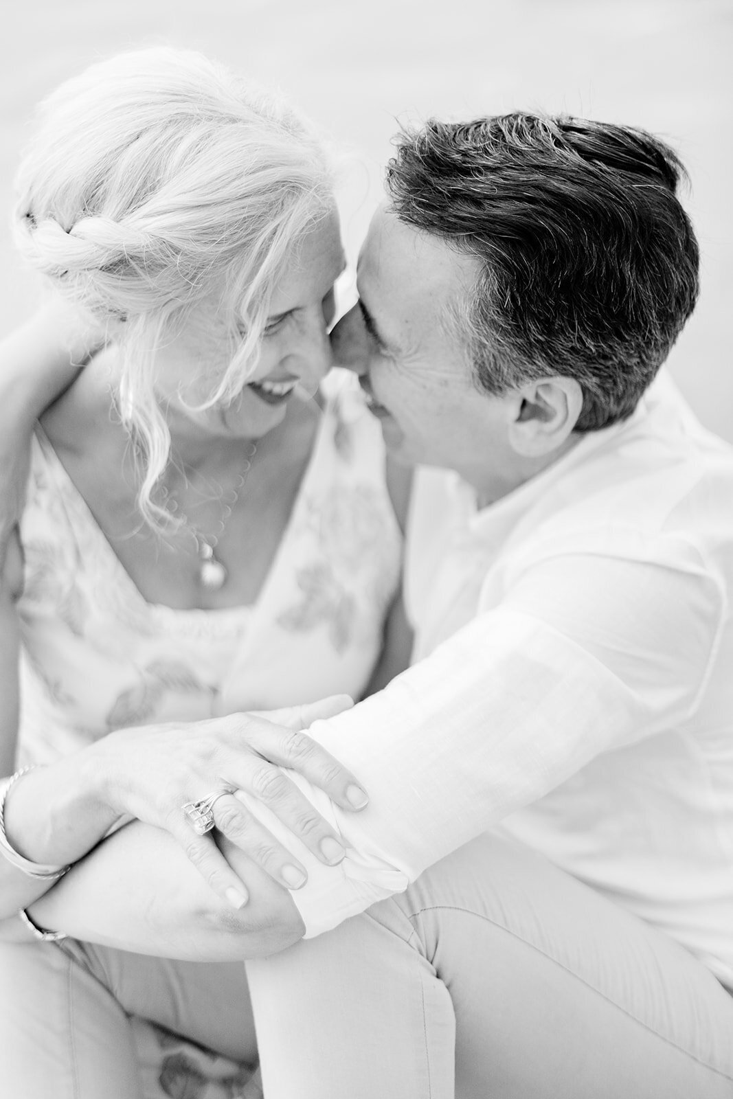 husband and wife hugging on the beach sitting down